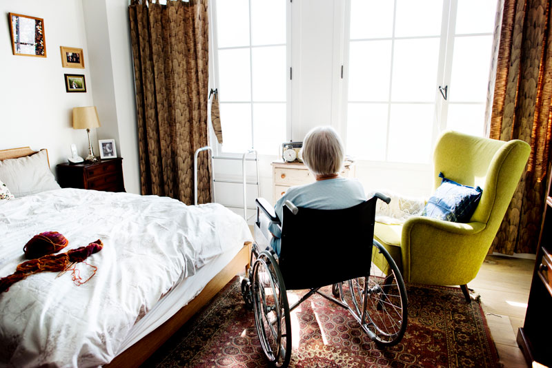Persona mayor en silla de ruedas en su habitación